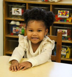 A female Black kindergarten student sitting at a table